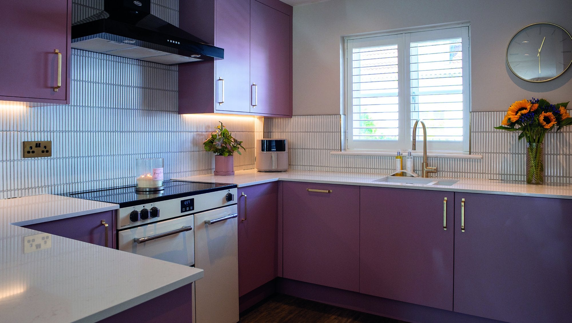 Dusky pink Romerils kitchen with Silestone worktops, Belling range cooker and gold Franke tap