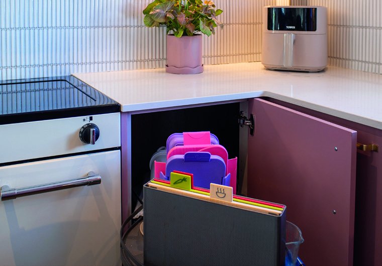Cream oven beside pink corner cupboard with pull-out storage
